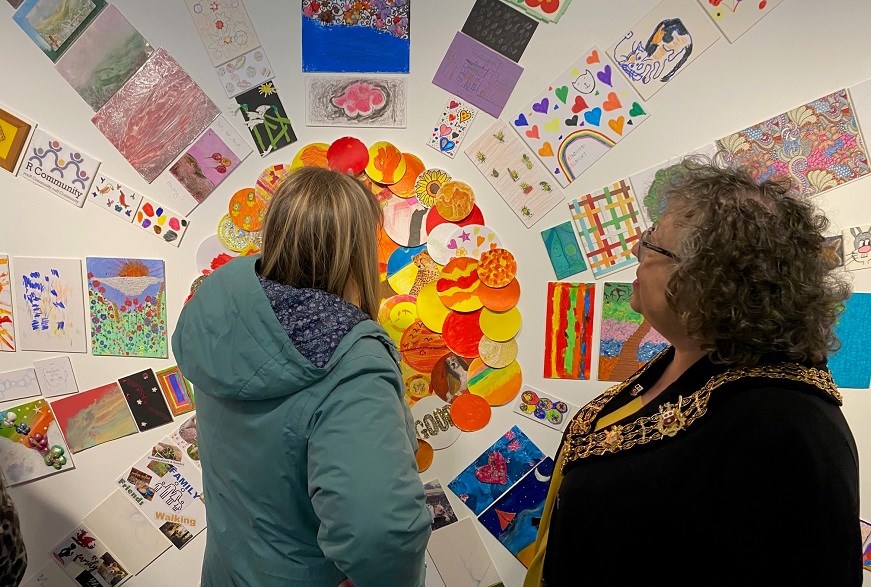 Lord Mayor Rayment with an artist looking at pieces of art on a wall