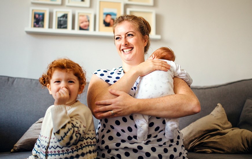 A woman with a child and baby, sitting on a sofa