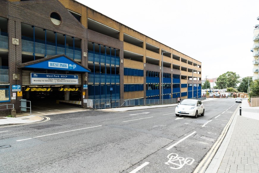 West Park Car Park from the outside. A car is driving along the road in front of it.