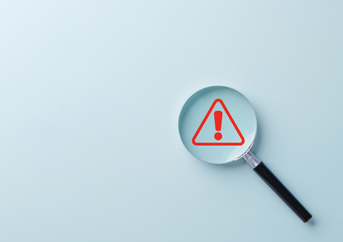 Magnifying glass over a warning symbol