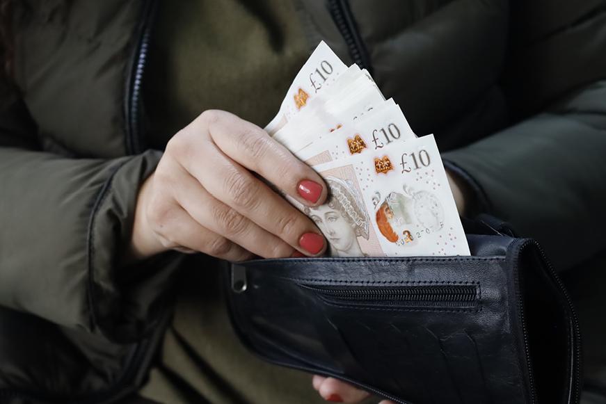 Someone Putting Money In A Wallet