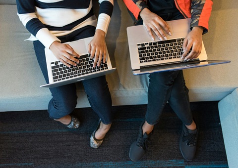 Two people side by side with laptop computers