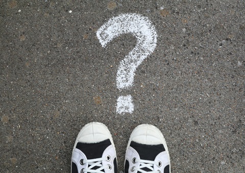 Feet standing on a chalk question mark
