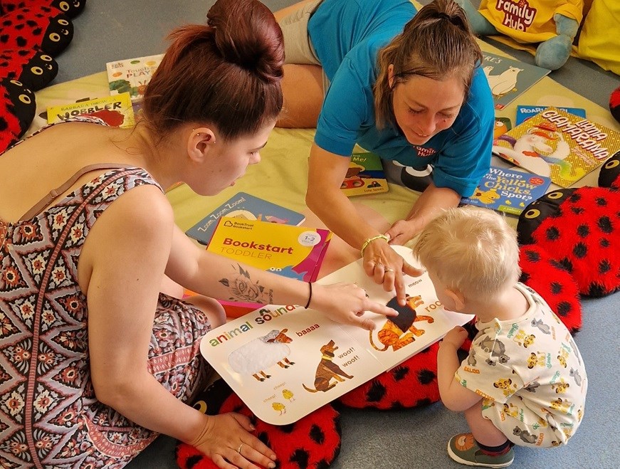 Family Hub staff and parent reading to young child