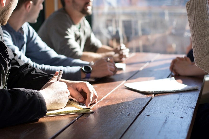 A group of people sitting around a table writing and talking