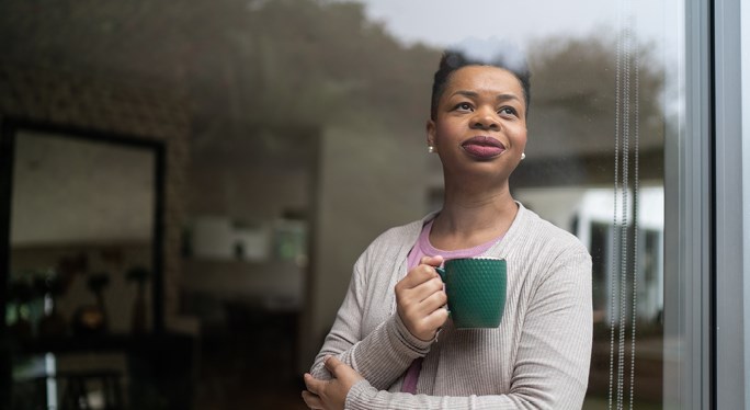 Woman holding a mug looking out of a window