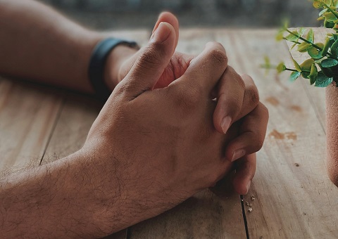 Clasped hands on table