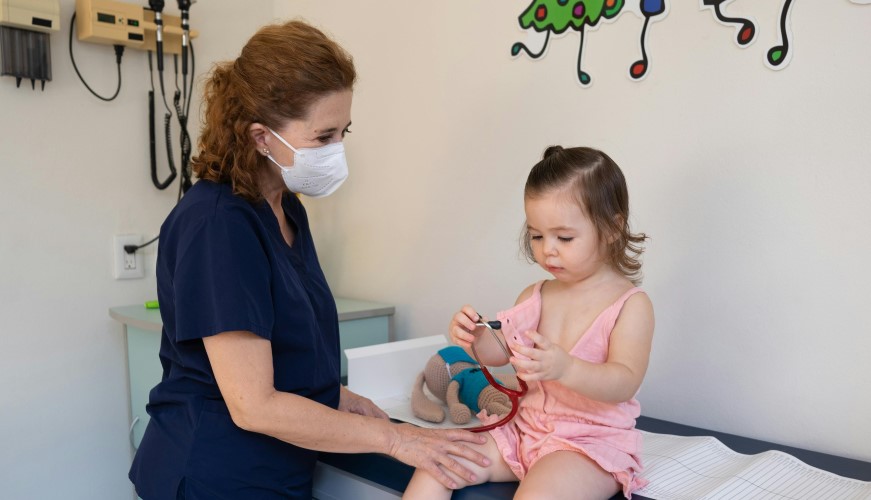 Child and nurse looking at a stethoscope