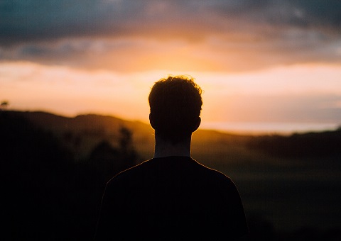 An adult silhouetted against the sunset