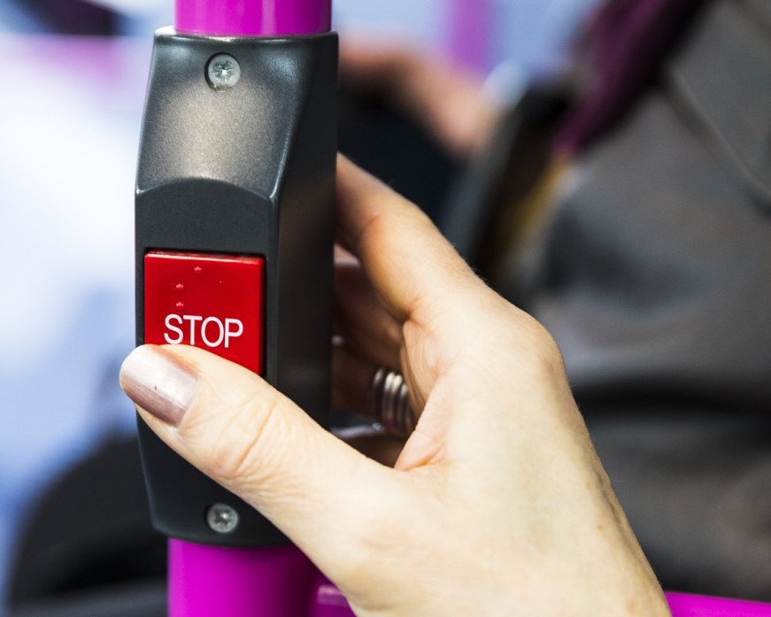 Button on a bus to let the driver know you want to get off at the next bus stop. It has braille markings on it and says "STOP" in all capital letters.