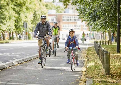 Two cyclists - parent and child - side-by-side on a park path