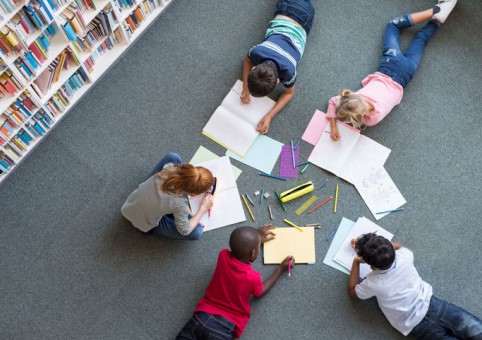 A group of children studying on a library floor