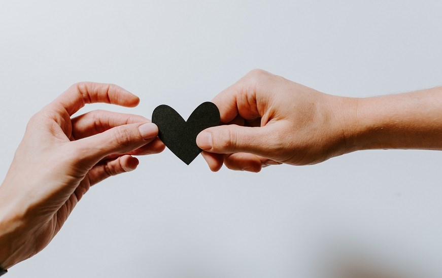 Two hands holding a black paper heart