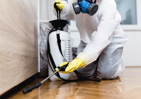 Someone in a protective suit spraying a sofa