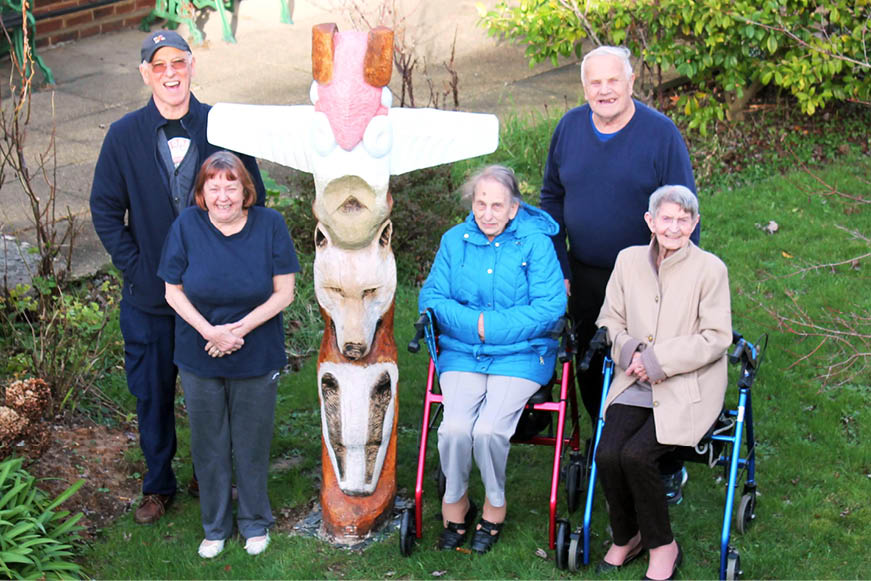 Five people posing with the new totem at Toronto Court