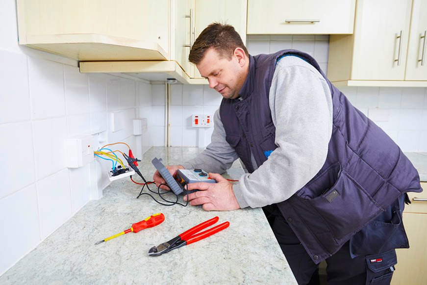 An electrician testing a wall socket