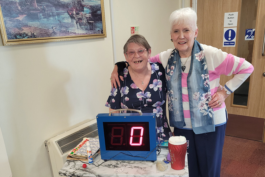 Two people standing with an electronic number display Two people standing with an electronic number display