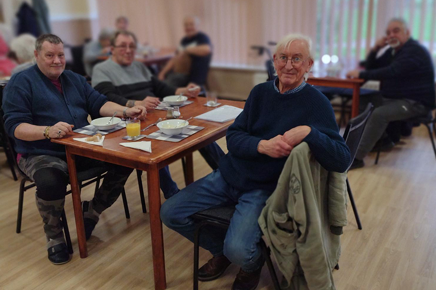 Several people sitting around tables set for lunch