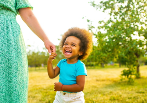 A happy child holding an adult's hand