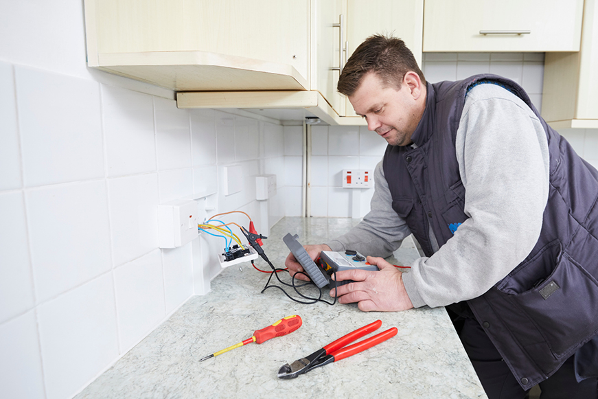 An electrician testing an electrical wall socket