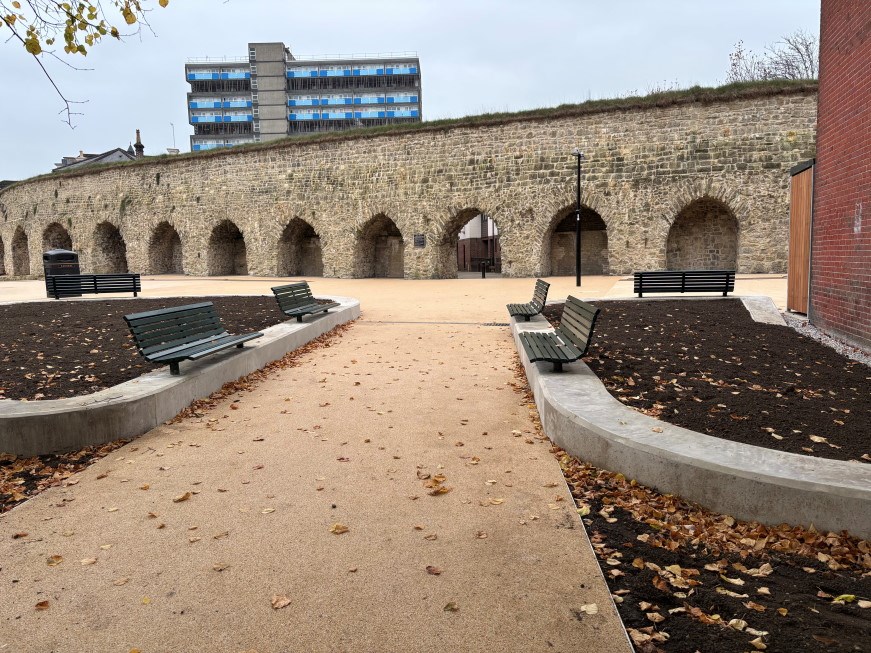 Neatly finished flower beds and benches in front of the wall arches