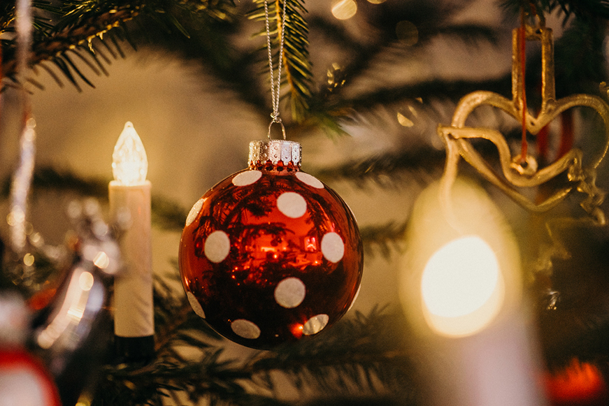 Decorations on a Christmas tree, including a candle-shaped light and a bauble