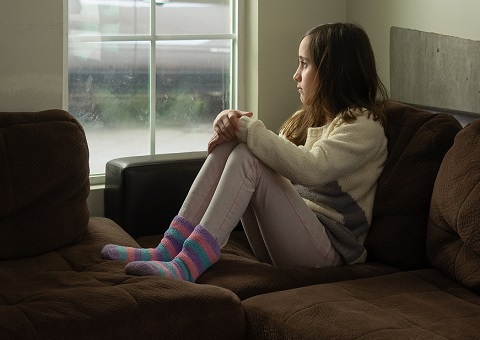 A young girl sitting and looking out of the window