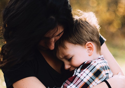 A mother closely holding her son