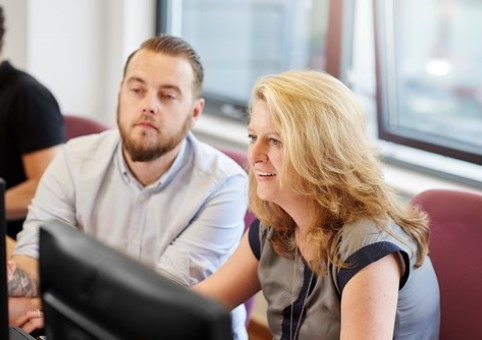 Two people talking while looking at a computer