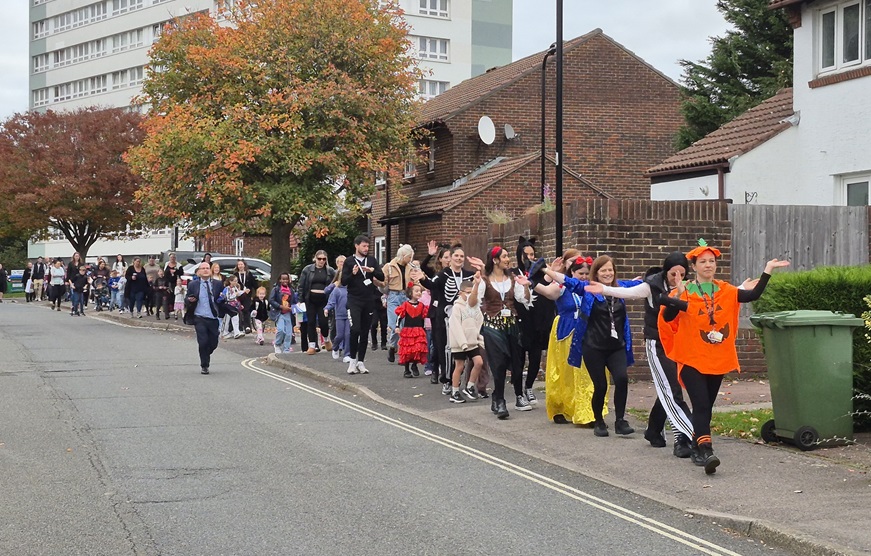 Kids and parents in fancy dress walking along the pavement