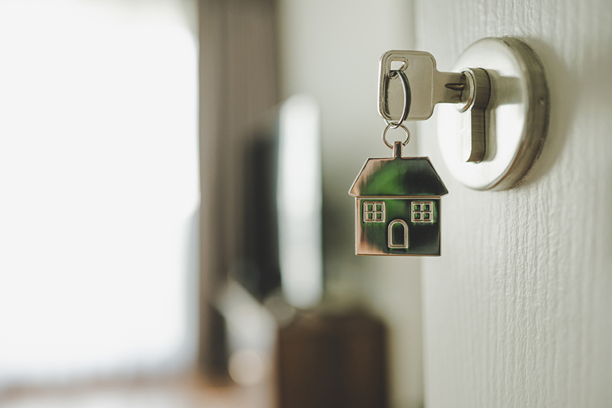 A key in a door lock attached to a house-shaped keyring