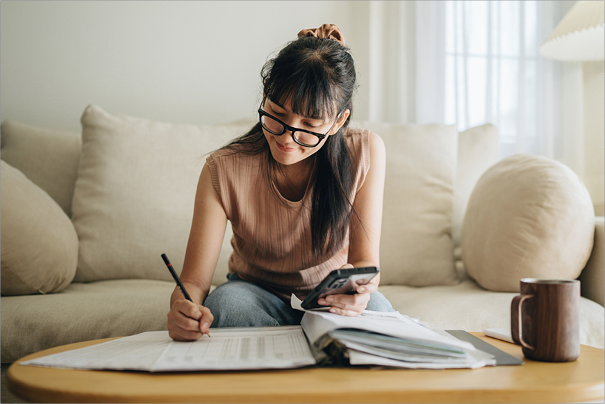 A happy woman doing her accounts in her living room