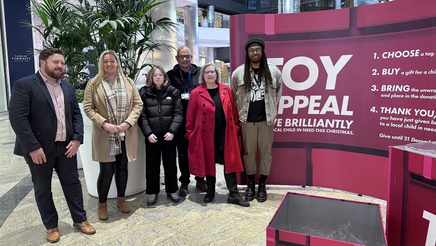 Councillor Alex Winning, Gemma Tizzard (Westquay), young person on work experience, Colin McPherson, Councillor Fielker and Aaron Sanchious (Westquay) in front of banner for Toy Appeal in Westquay